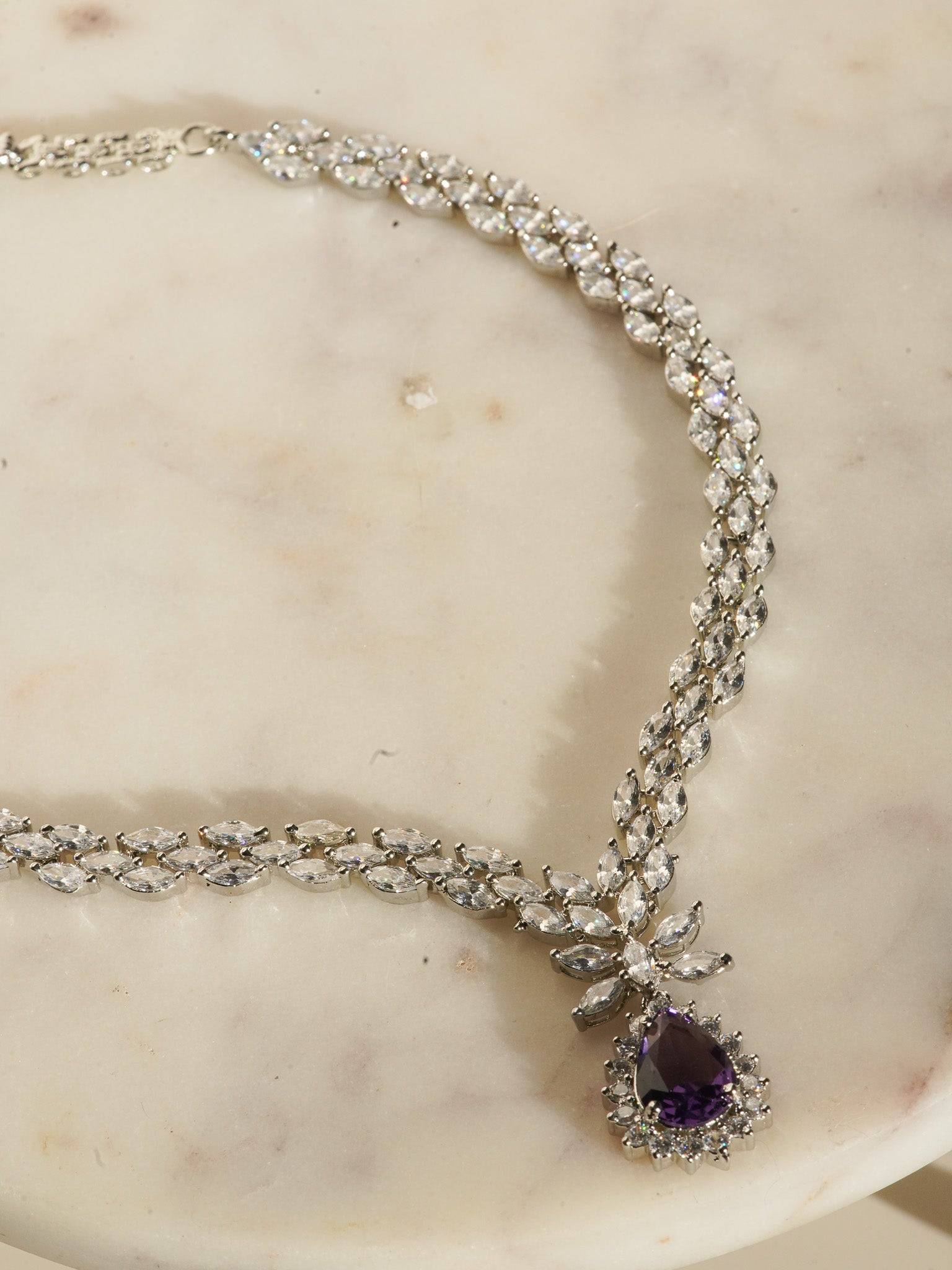 Lina Long Diamante Accent AD Necklace Set - Rhodium-plated with white AD stones, featuring intricate patterns and pendant-like centerpiece, available in silver & sapphire blue, silver & purple, and silver & citrine yellow, with matching dangling earrings.