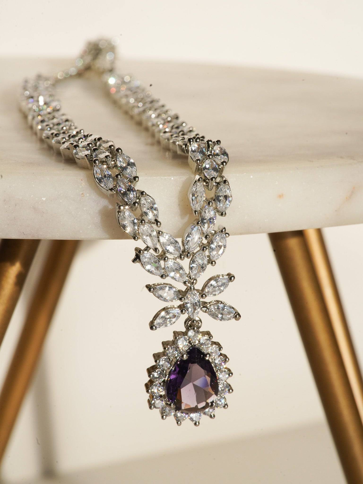 Lina Long Diamante Accent AD Necklace Set - Rhodium-plated with white AD stones, featuring intricate patterns and pendant-like centerpiece, available in silver & sapphire blue, silver & purple, and silver & citrine yellow, with matching dangling earrings.