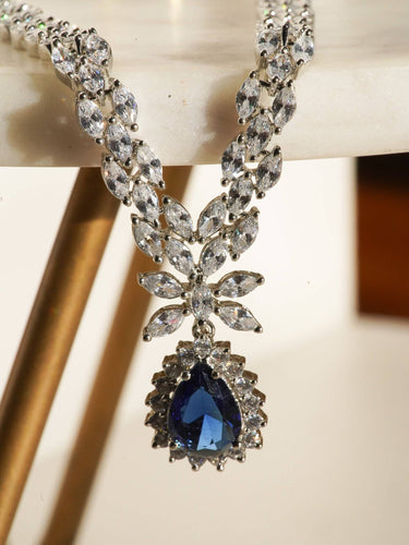 Lina Long Diamante Accent AD Necklace Set - Rhodium-plated with white AD stones, featuring intricate patterns and pendant-like centerpiece, available in silver & sapphire blue, silver & purple, and silver & citrine yellow, with matching dangling earrings.