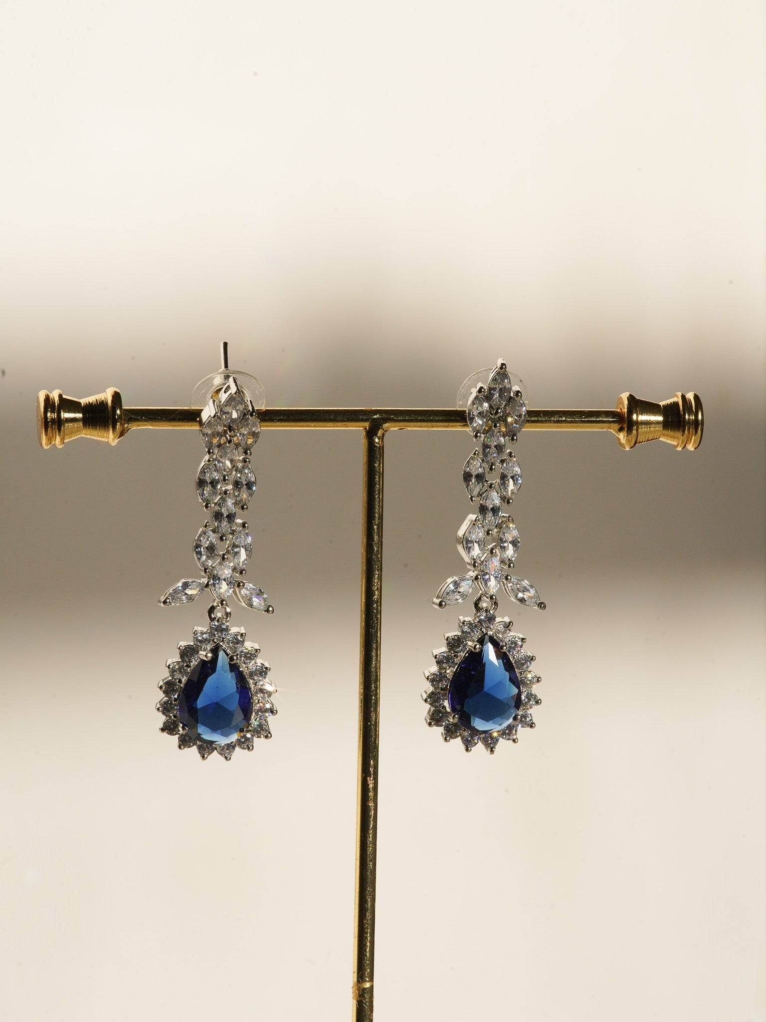 Lina Long Diamante Accent AD Necklace Set - Rhodium-plated with white AD stones, featuring intricate patterns and pendant-like centerpiece, available in silver & sapphire blue, silver & purple, and silver & citrine yellow, with matching dangling earrings.
