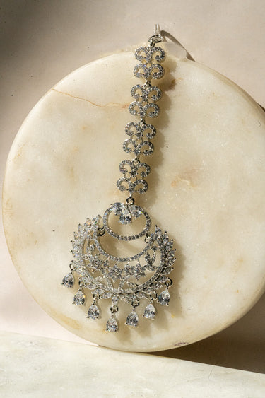 Liza Rhodium AD Maang Tikka in white with sparkling teardrop accents, ideal for weddings and festive occasions.