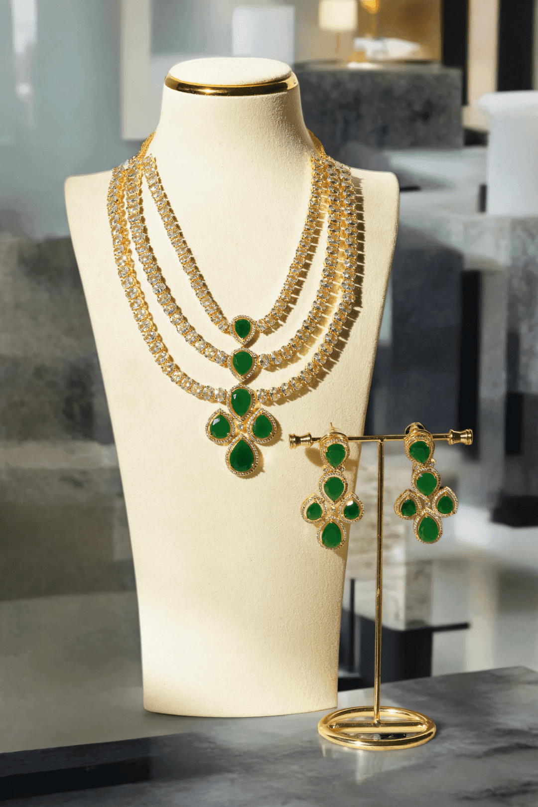 Niara Triple Layer Diamante Accent AD Necklace Set in gold or rhodium-plated silver finish with color options of silver & sapphire blue, silver & green, gold & green, and silver & ruby, featuring triple-layered chain links and matching statement earrings.