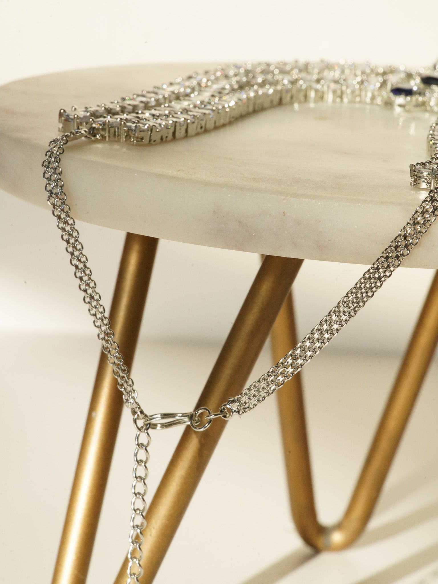 Niara Triple Layer Diamante Accent AD Necklace Set in gold or rhodium-plated silver finish with color options of silver & sapphire blue, silver & green, gold & green, and silver & ruby, featuring triple-layered chain links and matching statement earrings.