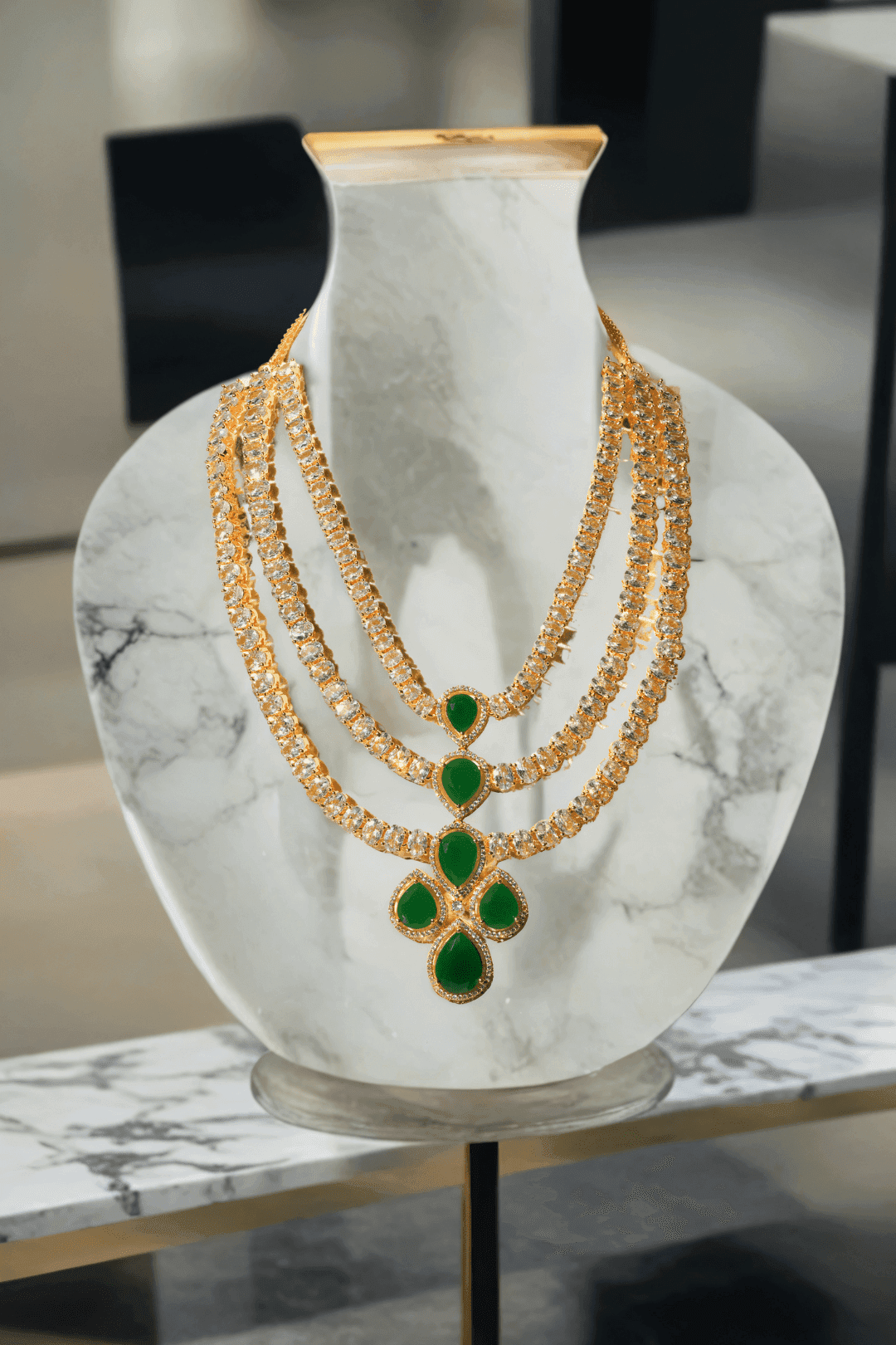 Niara Triple Layer Diamante Accent AD Necklace Set in gold or rhodium-plated silver finish with color options of silver & sapphire blue, silver & green, gold & green, and silver & ruby, featuring triple-layered chain links and matching statement earrings.