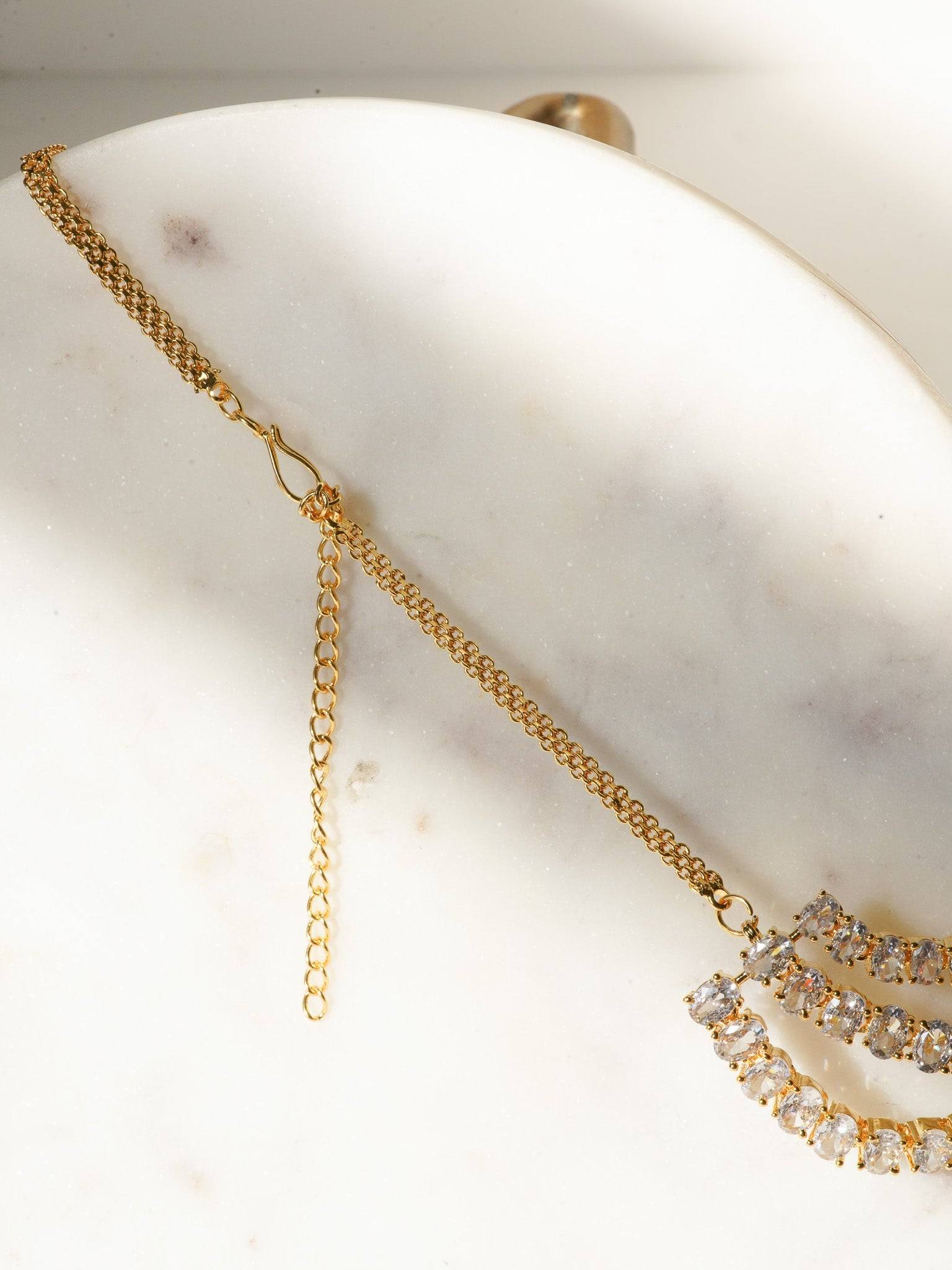 Niara Triple Layer Diamante Accent AD Necklace Set in gold or rhodium-plated silver finish with color options of silver & sapphire blue, silver & green, gold & green, and silver & ruby, featuring triple-layered chain links and matching statement earrings.