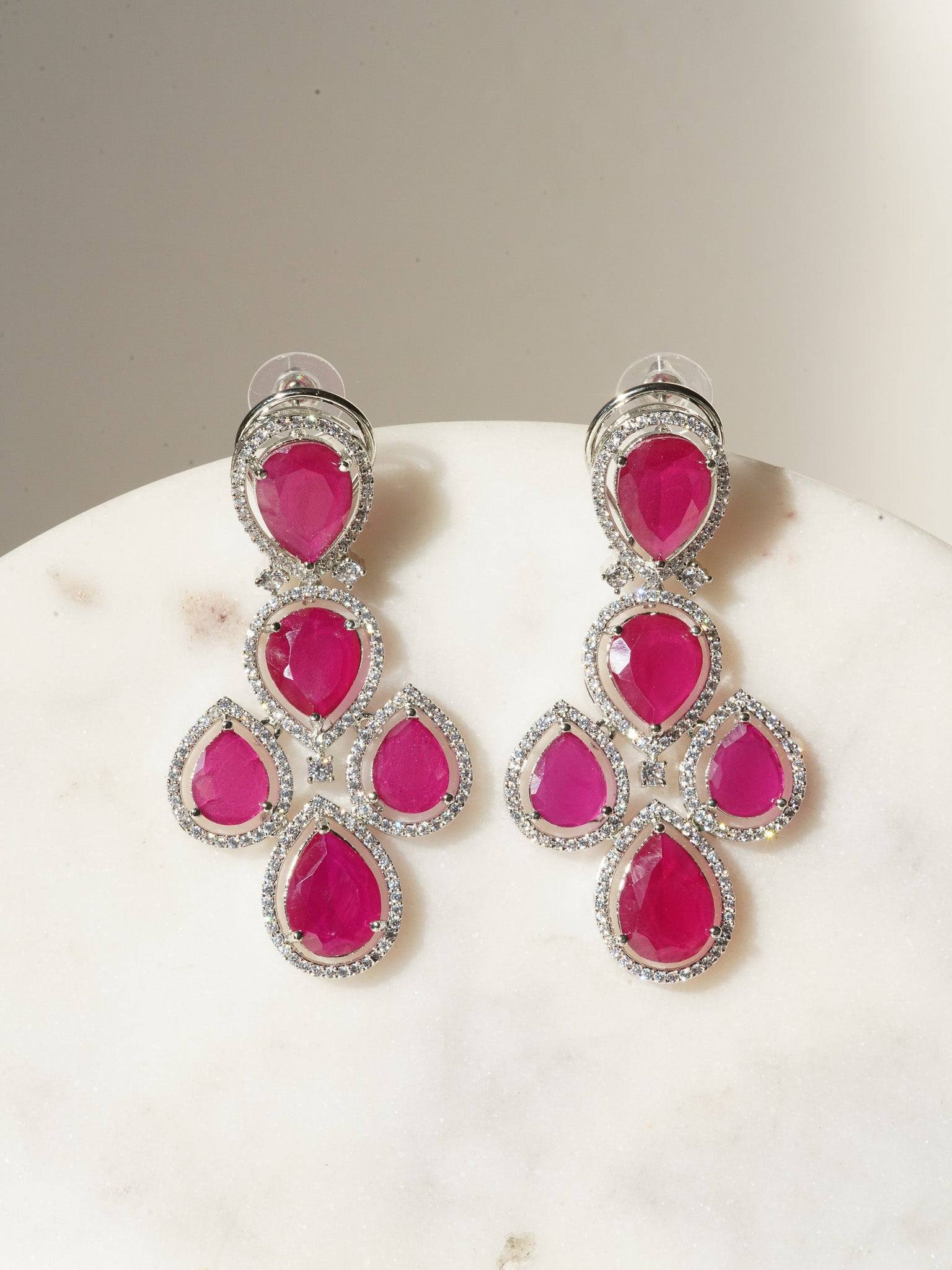 Niara Triple Layer Diamante Accent AD Necklace Set in gold or rhodium-plated silver finish with color options of silver & sapphire blue, silver & green, gold & green, and silver & ruby, featuring triple-layered chain links and matching statement earrings.
