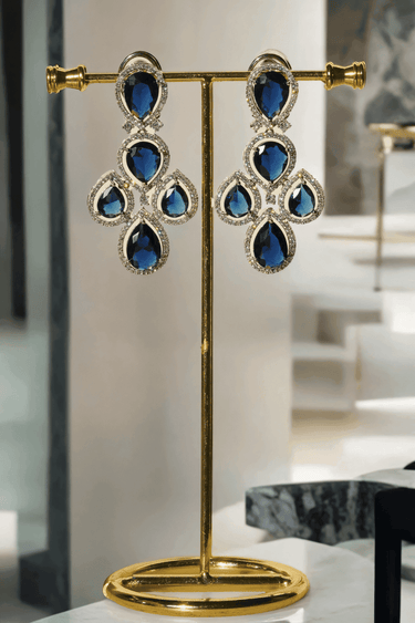 Niara Triple Layer Diamante Accent AD Necklace Set in gold or rhodium-plated silver finish with color options of silver & sapphire blue, silver & green, gold & green, and silver & ruby, featuring triple-layered chain links and matching statement earrings.