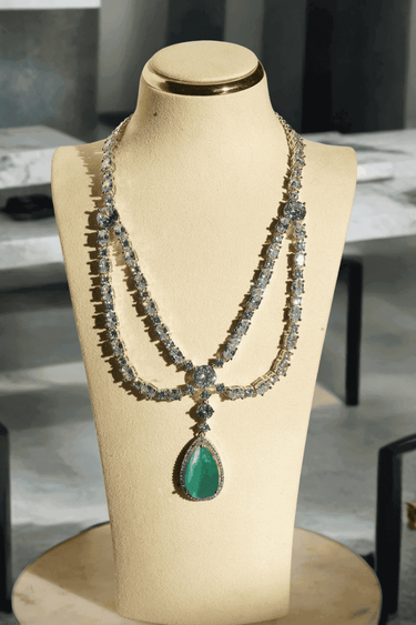 Nira Double Layered AD Necklace Set with criss-cross pattern, large teardrop pendant, and matching earrings in silver and mint green, silver and light pink, or silver and maroon.