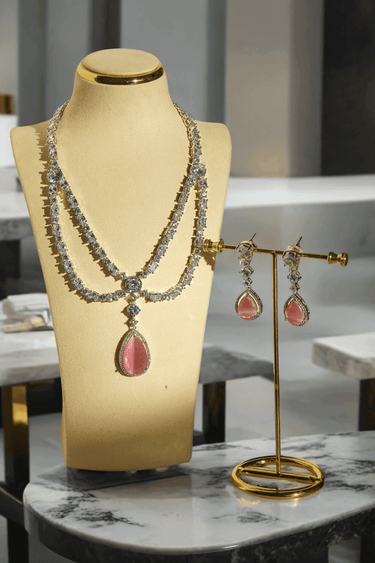 Nira Double Layered AD Necklace Set with criss-cross pattern, large teardrop pendant, and matching earrings in silver and mint green, silver and light pink, or silver and maroon.