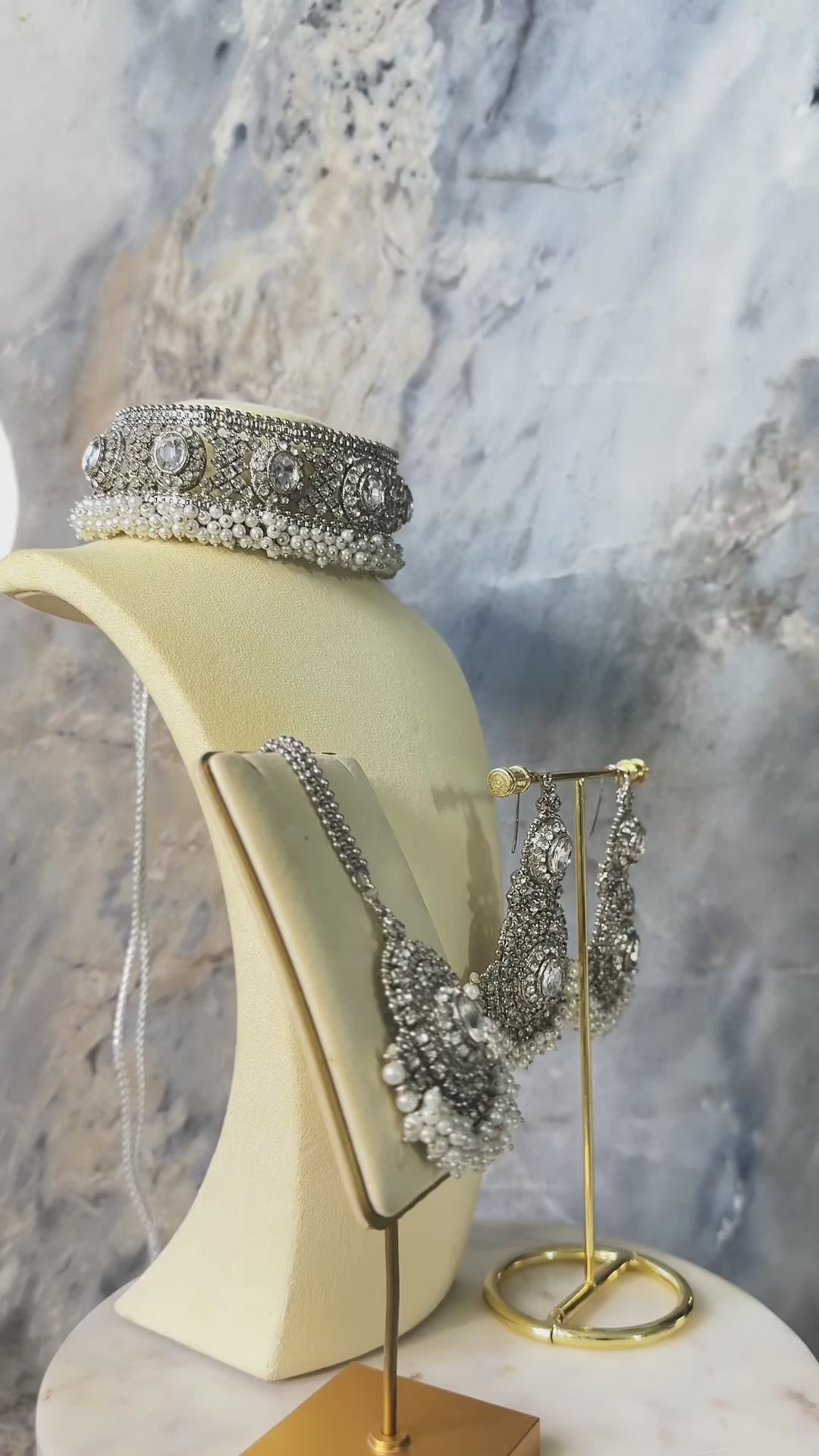 Silver-toned Rimmie Artisan Crafted Choker Set with zircon stones and pearl accents, displayed on a jewelry stand for elegant occasions.