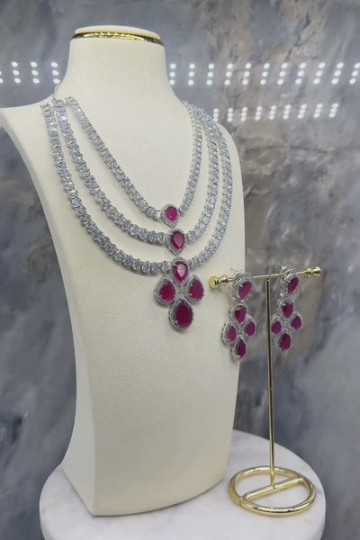 Niara Triple Layer Diamante Accent AD Necklace Set in gold or rhodium-plated silver finish with color options of silver & sapphire blue, silver & green, gold & green, and silver & ruby, featuring triple-layered chain links and matching statement earrings.