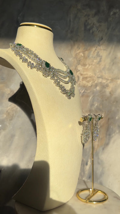 Neha Diamanté Accent Classic Necklace Set - Rhodium-plated with ruby or green accents, floral pattern, curvy layers, and matching 2-inch earrings.