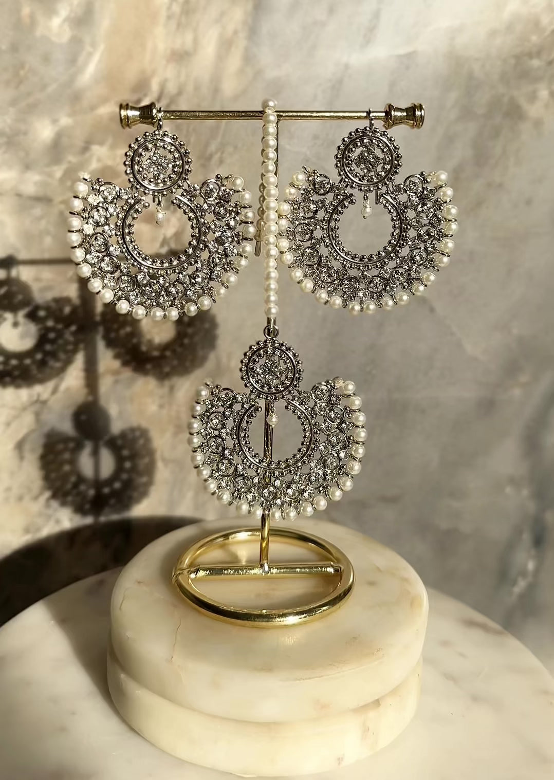 Antique gold Laila Chandbali Earrings and Maang Tikka Set with pearl rims, displayed on a gold stand with soft lighting.