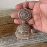 Handheld silver Tabiha Jhumka Earring with pink beads, showcasing detailed craftsmanship in traditional jewelry.