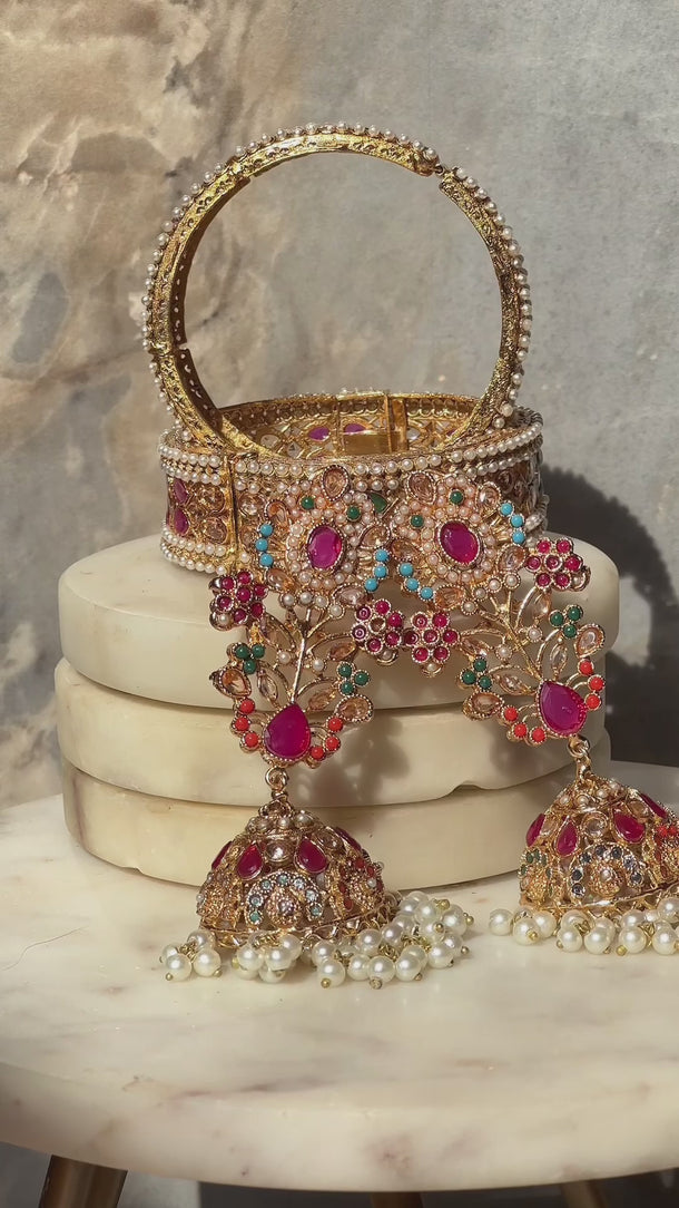 Close-up of Chaya Navratan jhumka earrings and gold bangle with multicolor stones, perfect for Indian bridal or festive wear.
