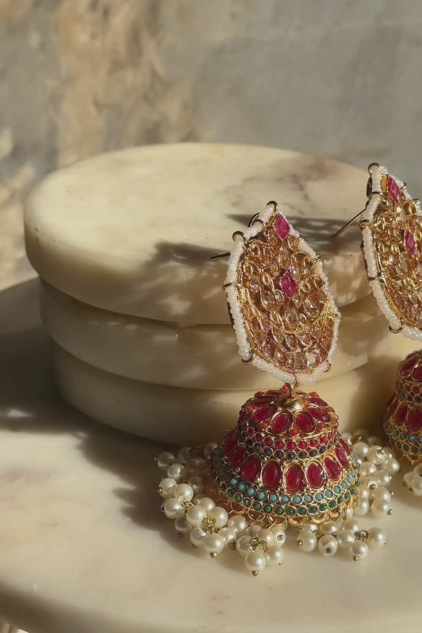 Close-up of Mishti Jhumkas showcasing ruby red stones, turquoise detailing, and pearl clusters, ideal for ethnic and bridal outfits.