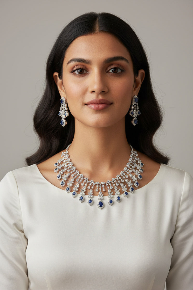 Raha Diamante Accent Classic Necklace Set with blue sapphire stones on model wearing ivory crew neck top
