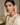 Woman wearing a beige top with floral Navratan statement stud earrings against a neutral background