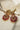 Front view of Adiva Statement Earrings with intricate gold, red, and green stonework and pearl fringe.