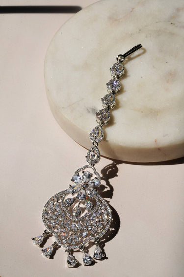 Rhodium-plated floral maang tikka with AD stones in a silver and white finish from Inaury