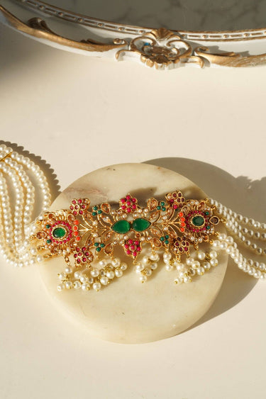 Close-up of Arushi Pearl Choker necklace with gold floral motifs, green Navratan stones, and pearl fringe.