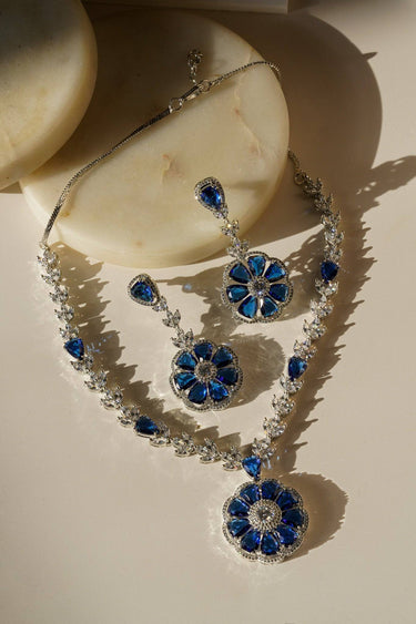 Chahat Necklace Set - Rhodium Floral AD in sapphire blue with teardrop and floral-cut stones. Includes matching earrings for a classic jewelry look.