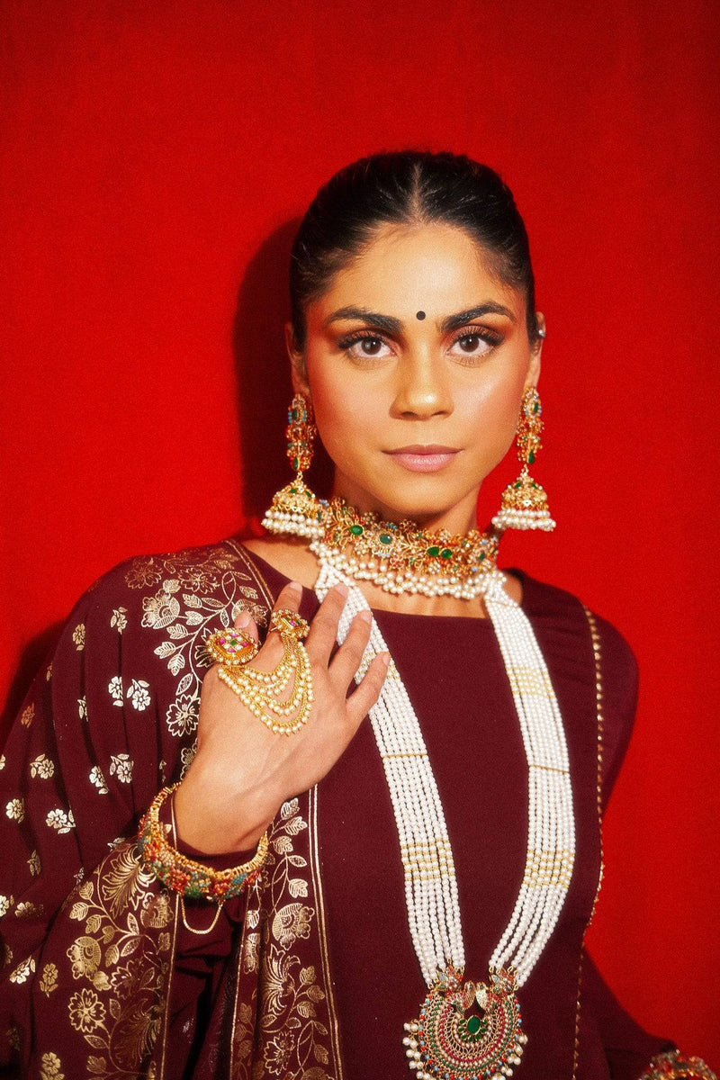 Model wearing Chaya Navratan choker necklace and jhumka earrings set in gold with multicolor stones, ideal for South Asian weddings and festivities.