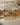Chaya Navratan choker necklace with green and red stones, gold filigree, and pearl fringe, displayed on a white surface.