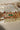 Chaya Navratan choker necklace with green and red stones, gold filigree, and pearl fringe, displayed on a white surface.