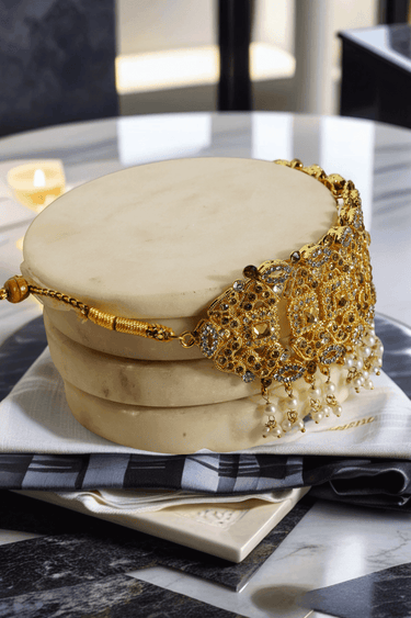 Back view of Esmeray Gold Choker Necklace showing adjustable clasp and intricate goldwork, laid on a marble base.