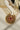 Detailed view of Inza Mala Necklace pendant with ruby centerpiece, multicolor stones, and pearl fringe on cream background.