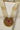 Zoomed-in shot of Inza Mala Necklace pendant highlighting intricate goldwork, red and green stones, and pearl detailing.