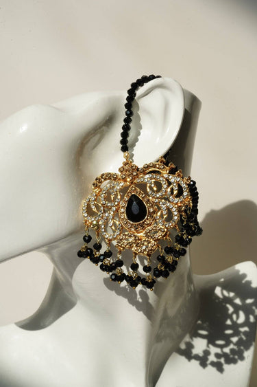 Close-up of Ira - Chandbali earring in black bead variant, showcasing intricate gold detailing and teardrop black stone centerpiece.