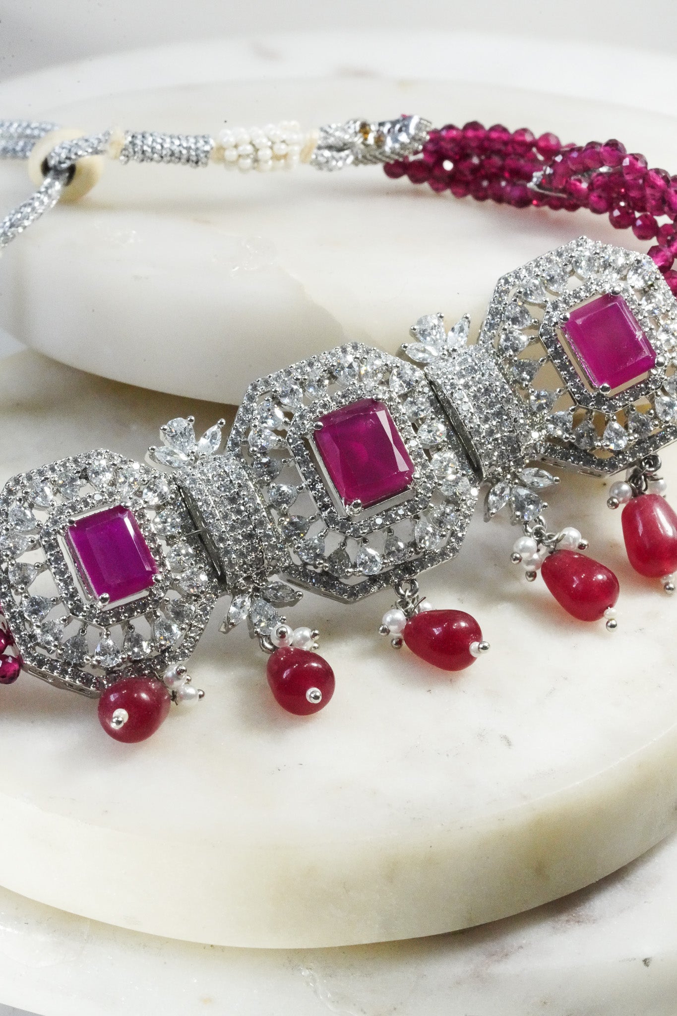Jhanvi Choker Necklace Set - Silver & Gem Variations featuring cushion-cut AD stones with ruby teardrop accents, includes matching earrings.