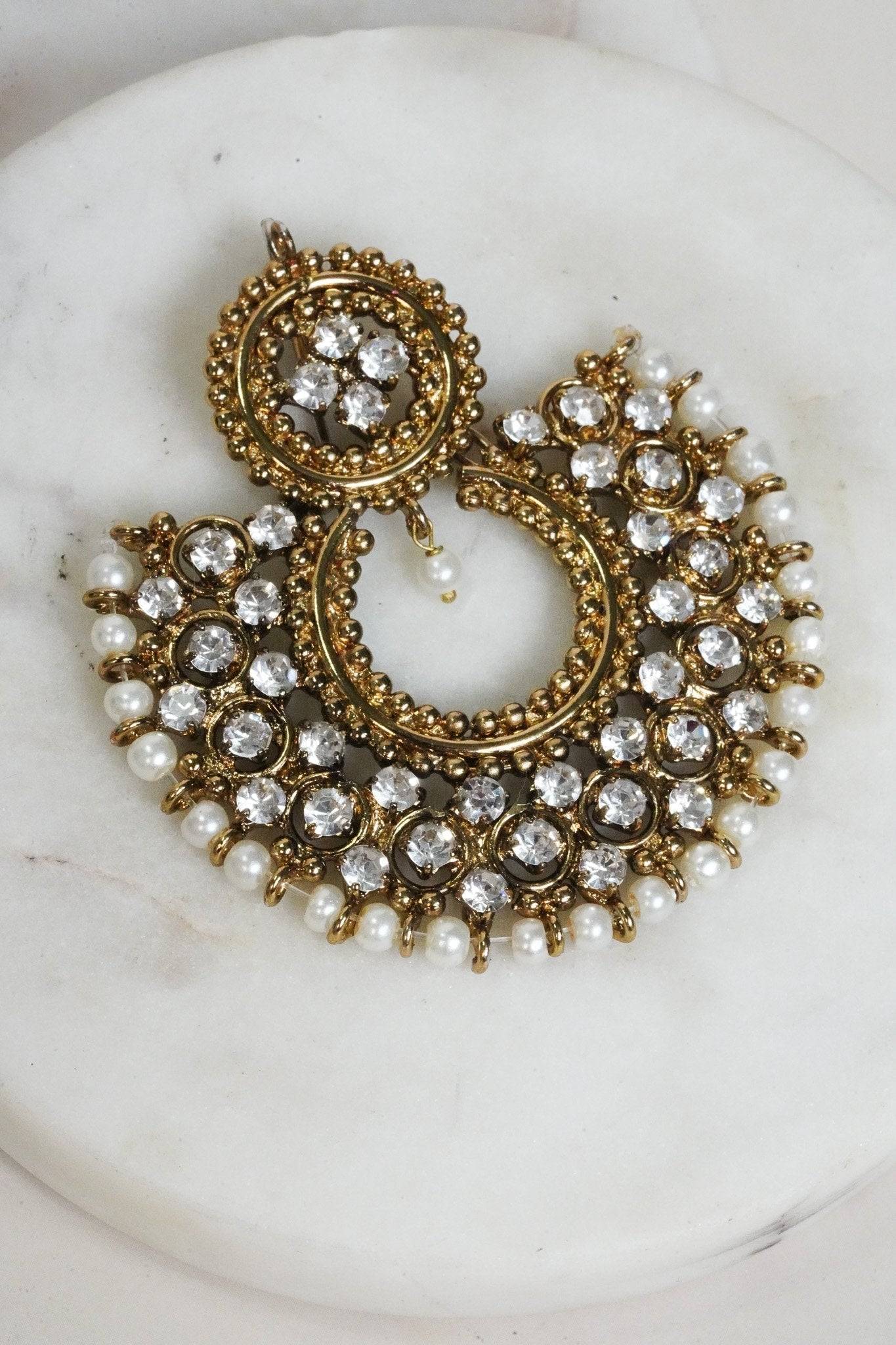 Laila Chandbali Earring in antique gold with dual-circle design, white stones, and pearl border, laid on a marble surface.