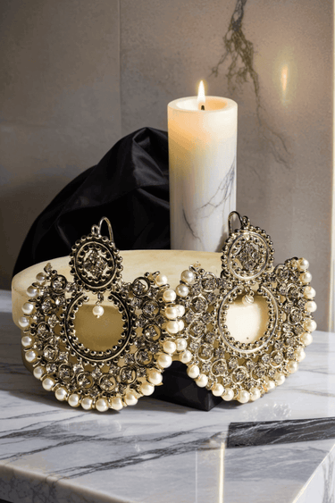 Laila Chandbali Earrings in antique gold with pearl borders, styled with a candle and marble decor for a festive look.