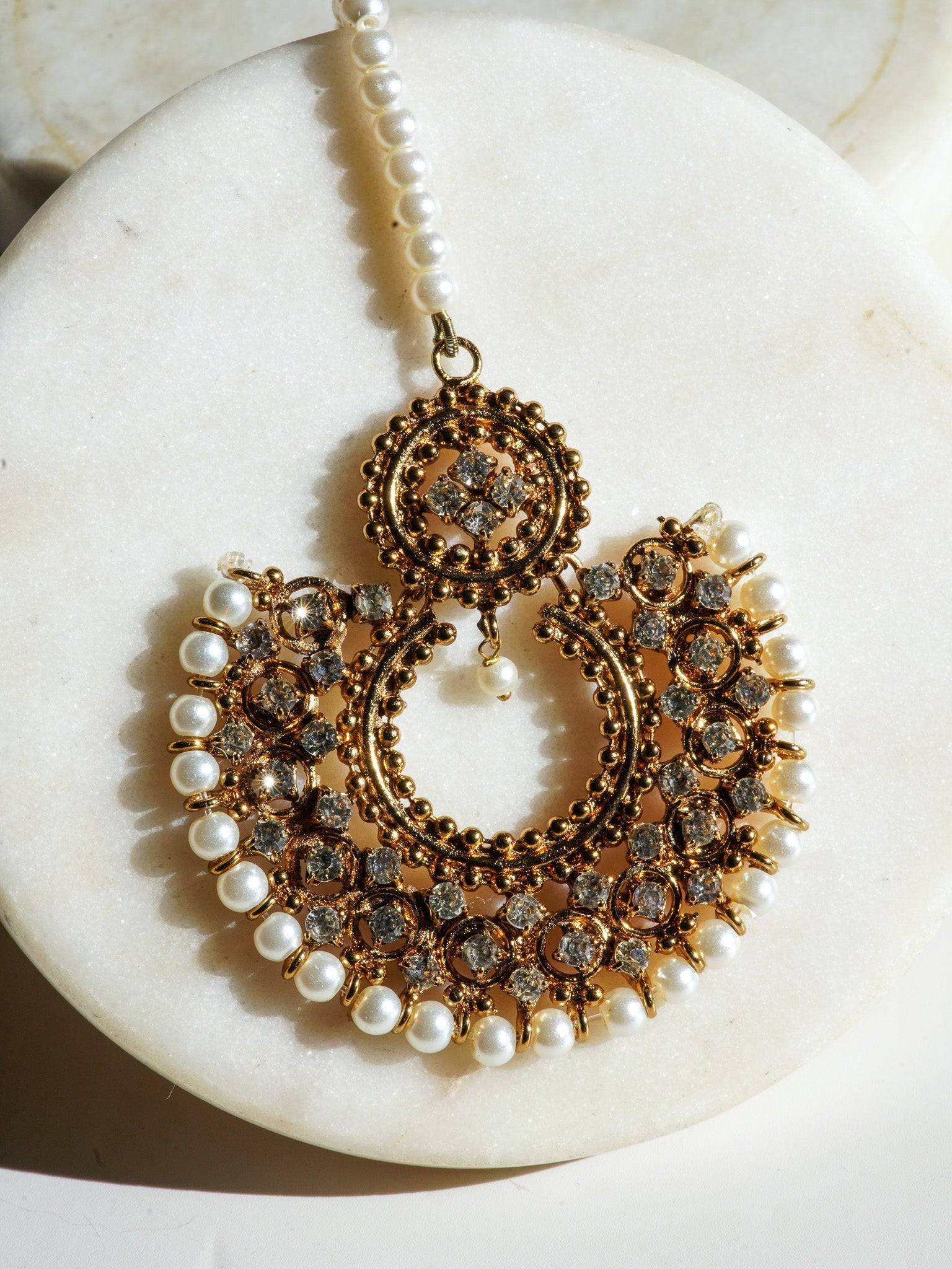 Close-up of Laila Maang Tikka in antique gold with white stones and pearl edging, ideal for traditional attire.