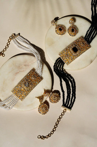 Flat lay of Luna Chic Choker Sets in black and pearl gold variants with matching earrings, perfect for chic fashion and jewelry collections.