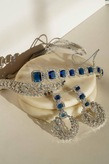 Mahi Asymmetrical Choker Necklace Set - Rhodium-plated with AD stones, available in silver & green, silver & ruby, and silver & sapphire blue, perfect for contemporary elegance.