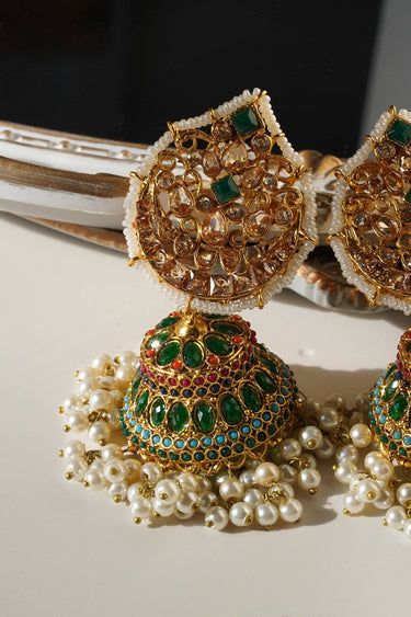 Detailed view of Mishti Jhumkas featuring emerald green stones, gold lattice work, and pearl hangings for a regal ethnic look.