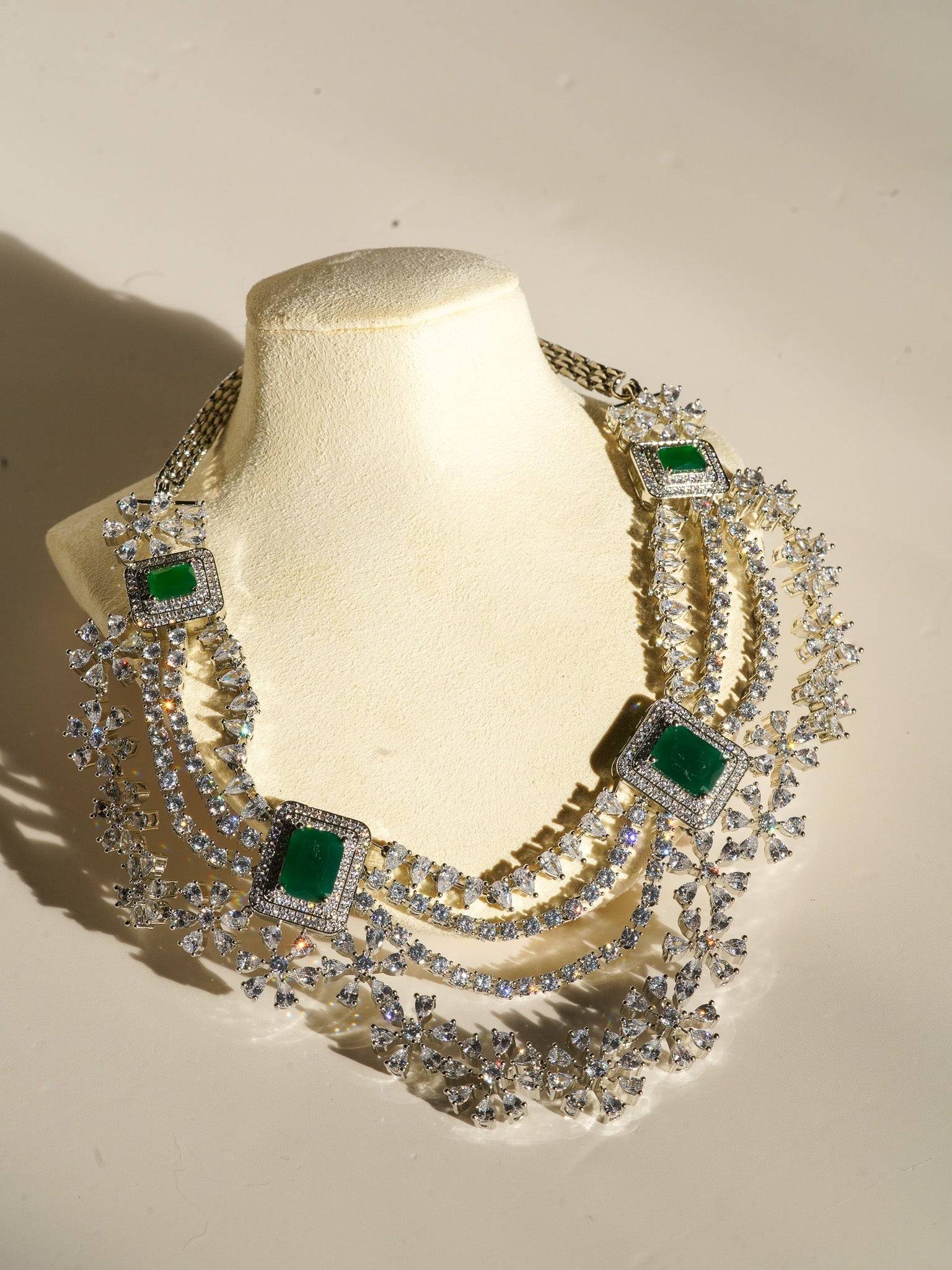 Neha Diamanté Accent Classic Necklace Set - Rhodium-plated with ruby or green accents, floral pattern, curvy layers, and matching 2-inch earrings.
