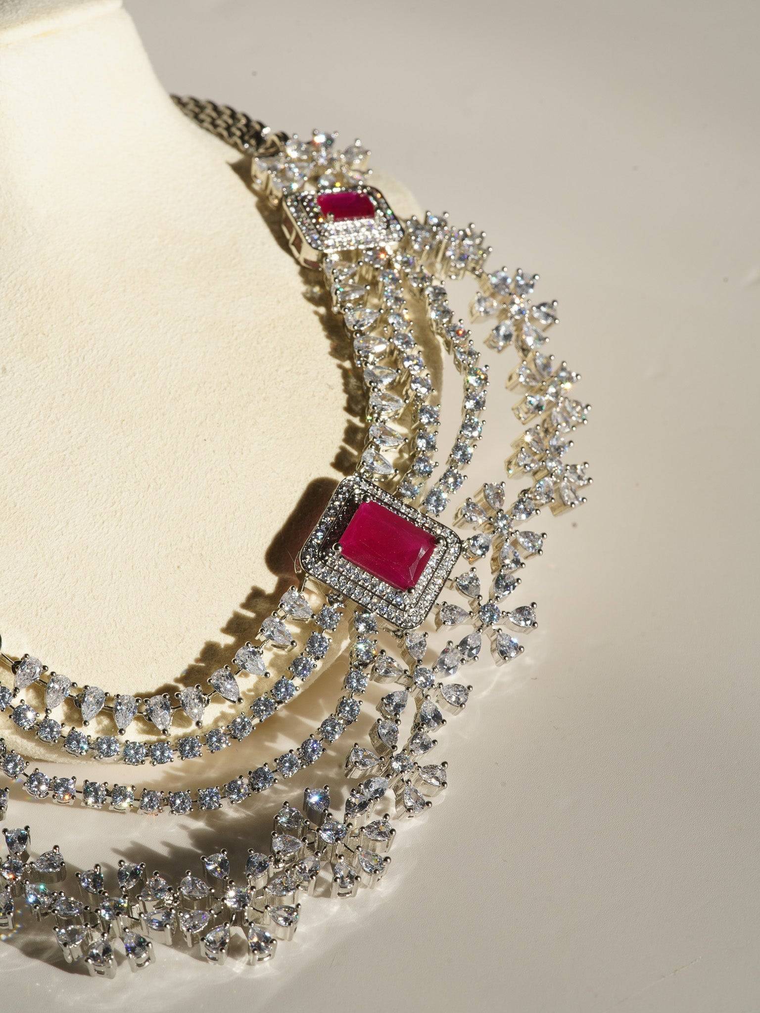 Neha Diamanté Accent Classic Necklace Set - Rhodium-plated with ruby or green accents, floral pattern, curvy layers, and matching 2-inch earrings.