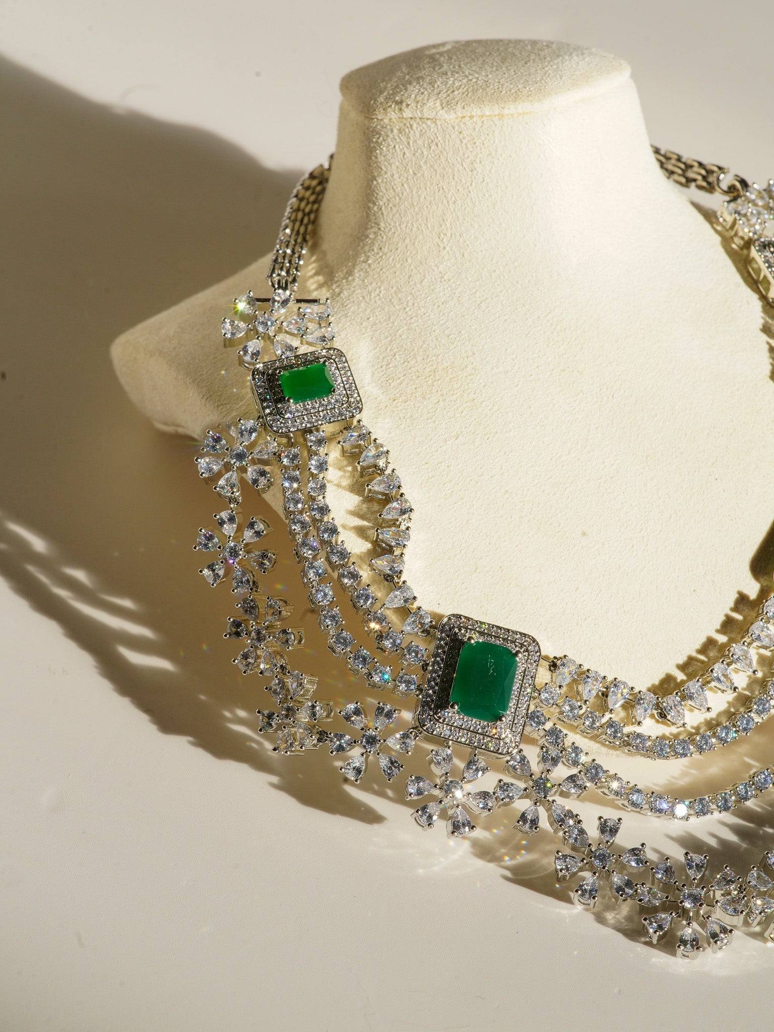 Neha Diamanté Accent Classic Necklace Set - Rhodium-plated with ruby or green accents, floral pattern, curvy layers, and matching 2-inch earrings.
