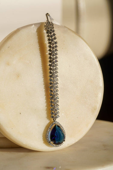 Safi - Rhodium-plated maang tikka with white American Diamonds and a sapphire blue teardrop accent from Inaury