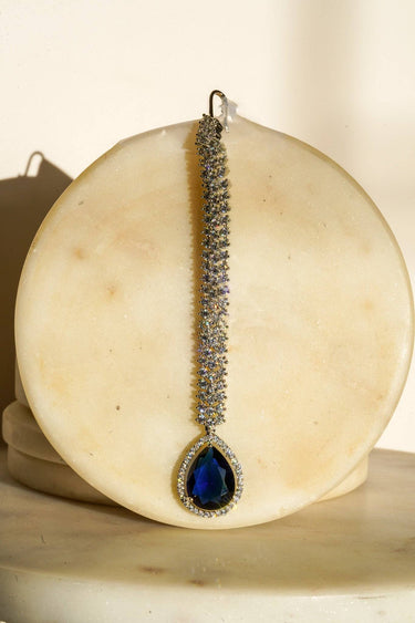 Safi - Rhodium-plated maang tikka with white American Diamonds and a sapphire blue teardrop accent from Inaury