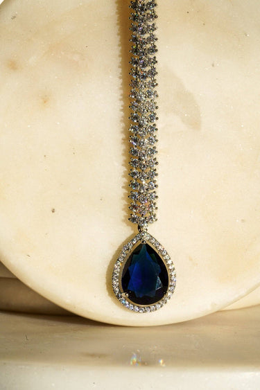 Safi - Rhodium-plated maang tikka with white American Diamonds and a sapphire blue teardrop accent from Inaury