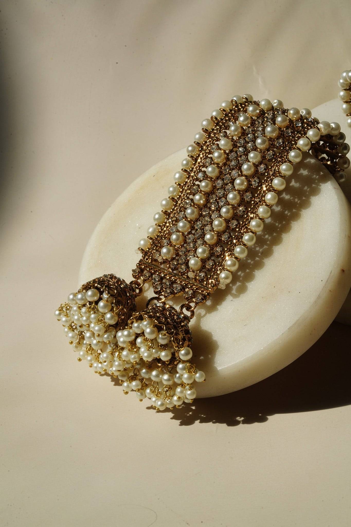Samia Bangles with pearl strands and gold jhumkas, laid on a round marble base, showcasing traditional Pakistani jewelry design.
