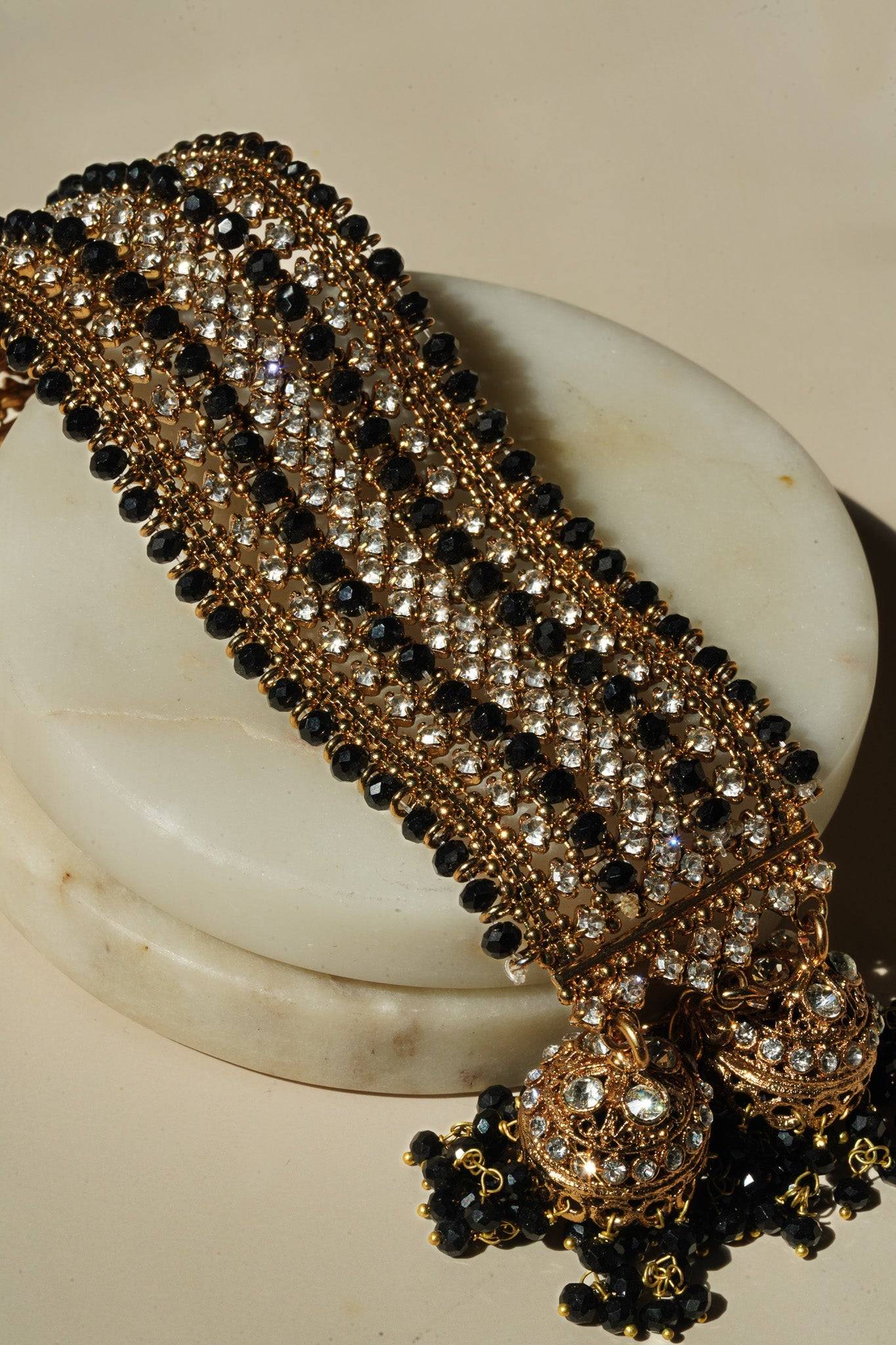 Angled view of Samia Bangles featuring black beads, CZ stones, and gold jhumkas, highlighting intricate traditional design.