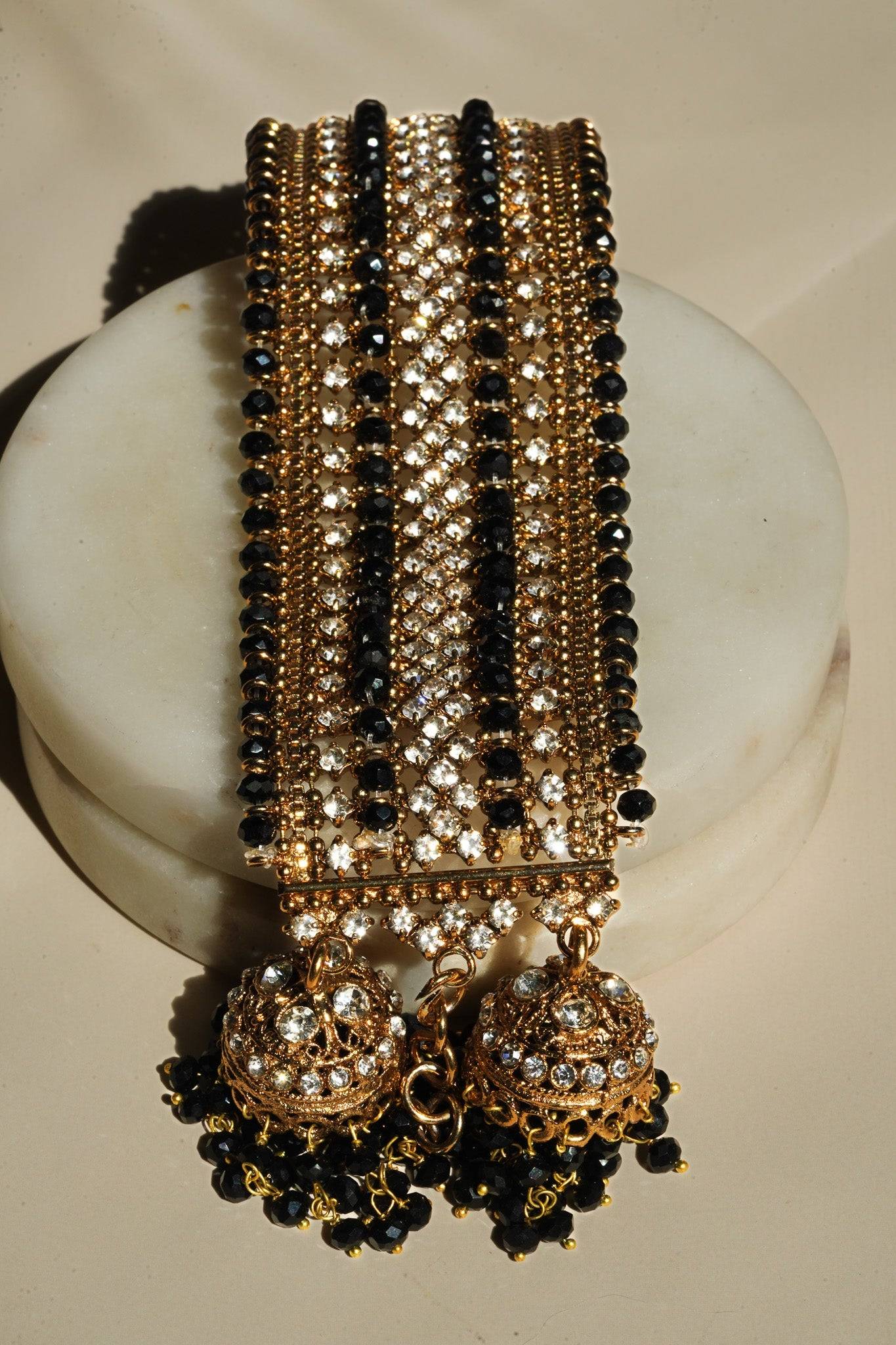 Top view of Samia Bangles in gold with alternating black beads and CZ stones, finished with dual jhumkas for festive elegance.