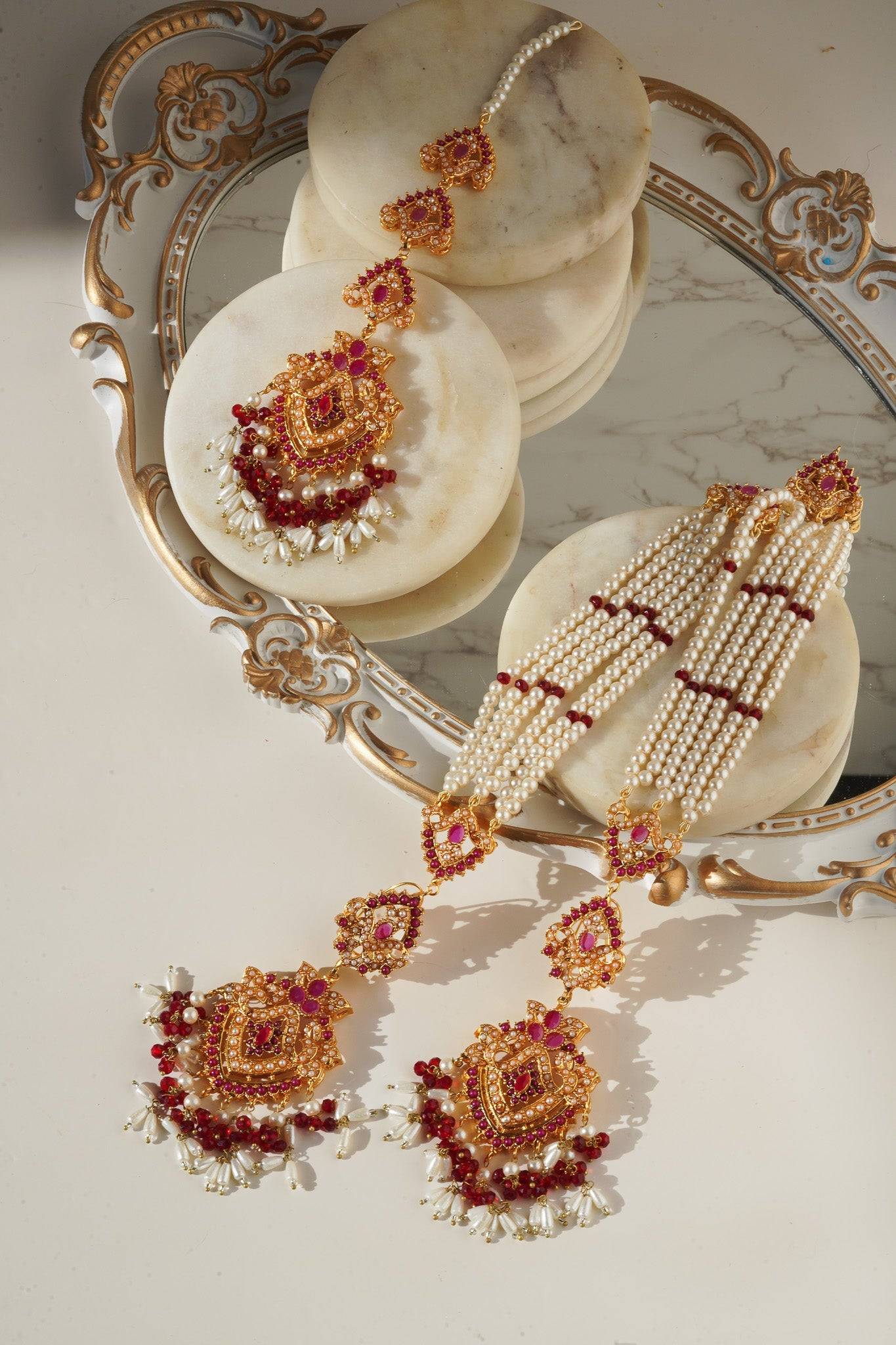 Sanjana Earrings and Maang Tikka Set in red and gold with pearl strands, perfect for bridal and festive occasions.
